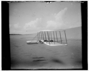 Wilbur Wright in prone position on glider just after landing, its skid marks visible behind it and, in the foreground, skid marks from a previous landing; Kitty Hawk, North Carolina (1901; LOC - LC-DIG-ppprs-00570)