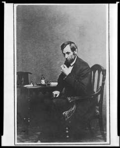 President Abraham Lincoln, seated next to small table, in a reflective pose, May 16, 1861, with his hat visible on the table (between 1885 and 1911, from photo taken on 1861 May 16; LOC: LC-USZ62-15178)