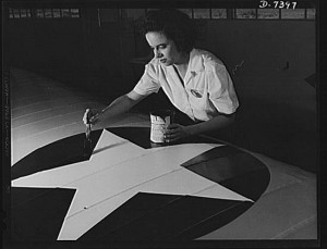 Naval air base, Corpus Christi, Texas. Women from all fields have joined the production army. Miss Grace Weaver, a civil service worker at the Corpus Christi naval air base and a school teacher before the war, is doing her part for Victory along with her brother who is a flying instructor in the Army. Miss Weaver paints the American insignia on repaired Navy plane wings (1942 Aug; LOC: LC-USE6-D-007397)
