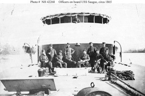 USS Saugus (1864-1891)  Officers pose on deck, in front of the gun turret, probably while the ship was serving on the James River, Virginia, in early 1865.  U.S. Naval Historical Center Photograph.