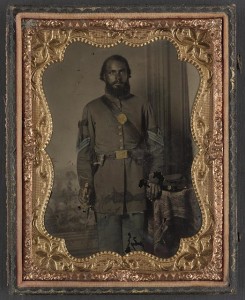 Unidentified African American soldier in Union infantry sergeant's uniform and black mourning ribbon with bayonet in front of painted backdrop (between 1863 and 1865; LOC:  LC-DIG-ppmsca-34365)