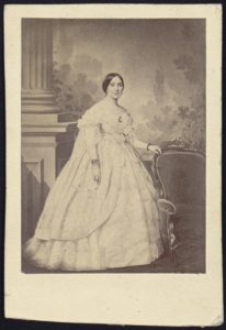 Mrs. Jefferson Davis, full-length studio portrait, standing, facing slightly right with left hand resting on the back of a chair (between 1860 and 1870; LOC: https://www.loc.gov/item/2005677223/)