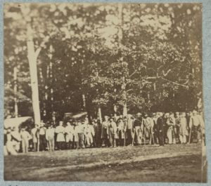 Group of soldiers, some in uniform and some with crutches, pose in front of the woods at the hospital at Camp Letterman in Gettysburg (LOC: https://www.loc.gov/item/2014645949/)