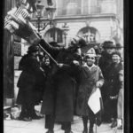 Flag-vendor and boy in the Rue St. Honore, Paris. Everybody wanted flags to wear and to wave while celebrating the signing of the Armistice with Germany (Nov. 11, 1918; LOC: https://www.loc.gov/item/2017675343/)`
